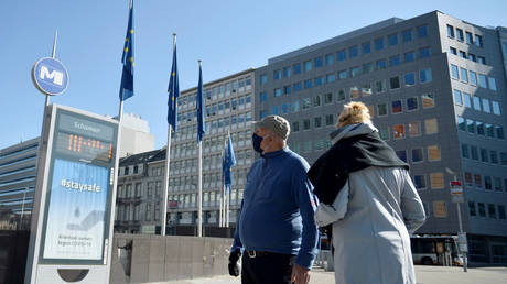 FILE PHOTO. A couple wearing protective face masks walks past the European Commission headquarters in Brussels, Belgium.