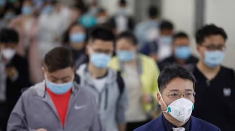 People wearing face masks walk inside a subway station during morning rush hour in Beijing