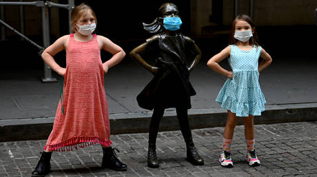 Two young girls pose by the masked bronze sculpture of the "Fearless Girl"  in front of the New York Stock Exchange (NYSE)  in New York City.